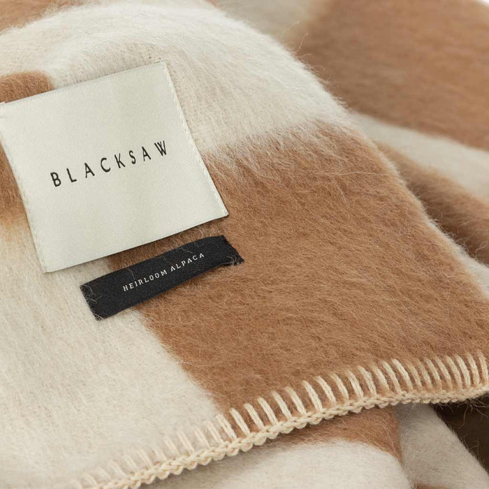 The Blacksaw Checkerboard Crosby Blanket in Tabacco BrownClose Up product shot showing beautiful Blacksaw brand label, Heirloom Alpaca label and Blanket Stitching detail